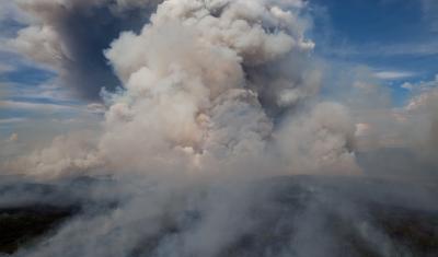 A smoke column rises from the Alaskan forests