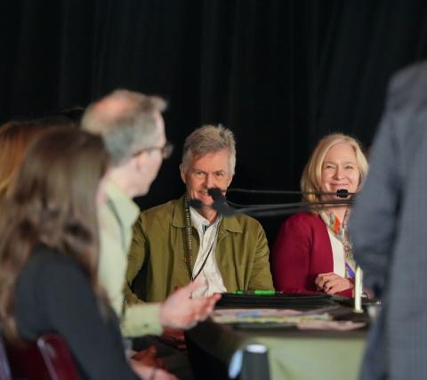 The camera looks over the shoulder of a panelist who is speaking to two members of the California Wildfire and Forest Resilience Task Force's executive commitee sitting to his left.