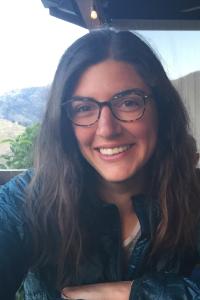 Woman with glasses and long hair sitting by window