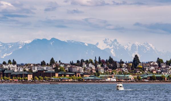 A village by the shore with mountains covered in snow in the distance
